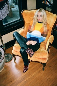a woman in a colorful sweater sitting in a chair