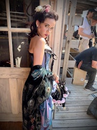 a woman in a costume is posing on a wooden deck