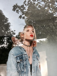 a woman wearing a denim jacket and red lipstick