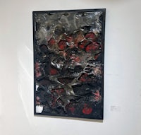 a black and red painting hanging on a wall